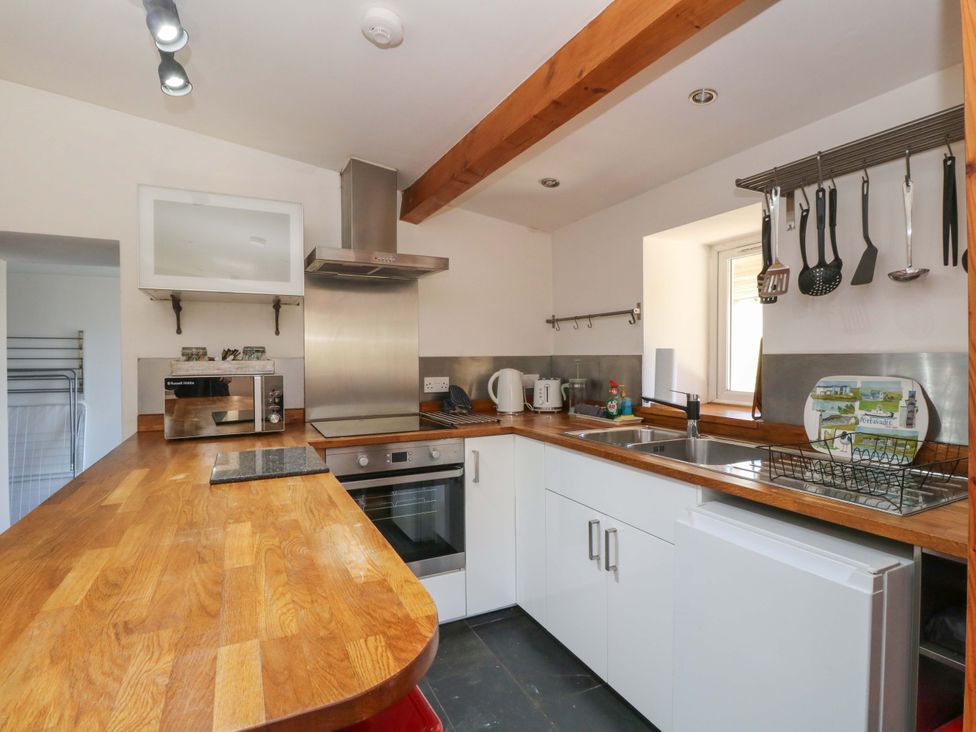 A kitchen with a counter, sink, oven, and microwave at Gun Powder Cottage Tighnabruaich