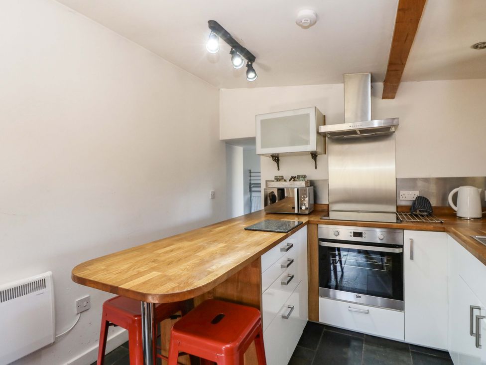 A kitchen with countertop and stools at Gun Powder Cottage in Tighnabruaich