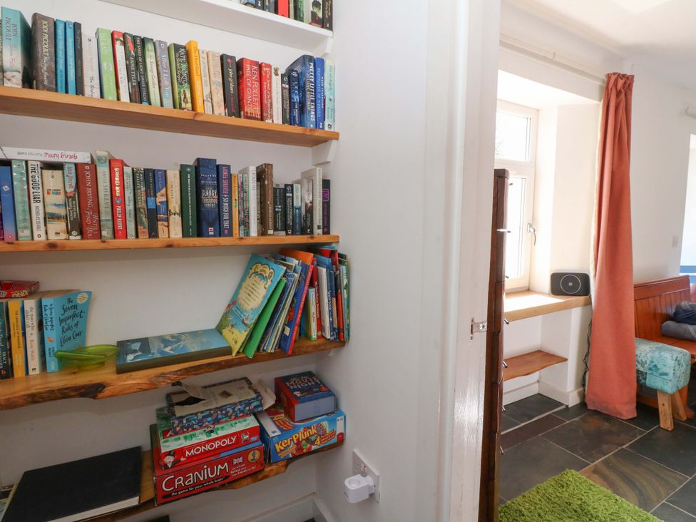 A reading area with bookshelves and games at Gun Powder Cottage in Tighnabruaich