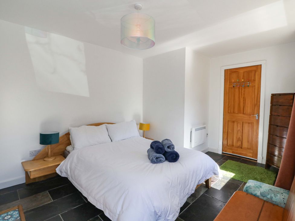 A bedroom with a bed and nightstand at Gun Powder Cottage Tighnabruaich