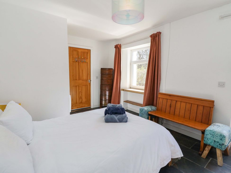 A bedroom with a bed and bench at Gun Powder Cottage Tighnabruaich