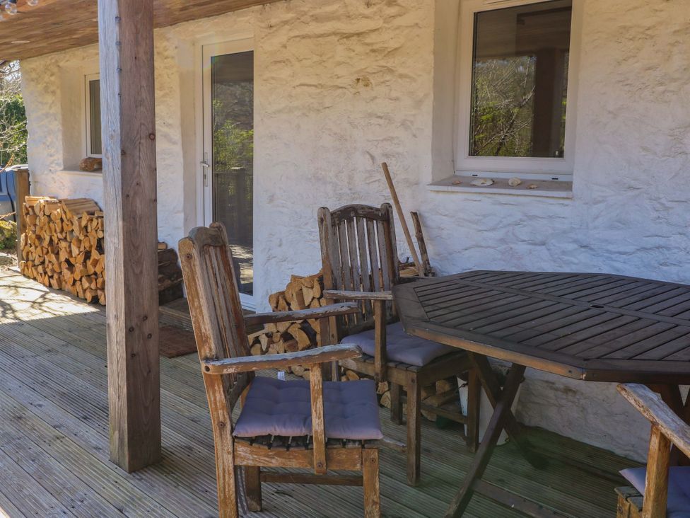 An outdoor sitting area with wooden table and chairs at Gun Powder Cottage in Tighnabruaich