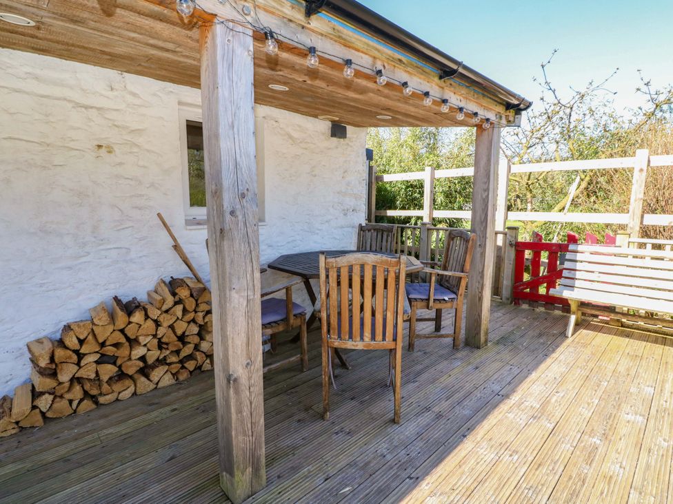 A deck with a wooden table and chairs at Gun Powder Cottage in Tighnabruaich