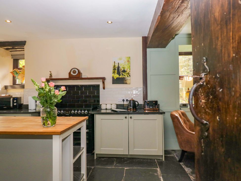 A kitchen with a wooden table and flower vase at Ewedale Farm in Pennington near Ulverston