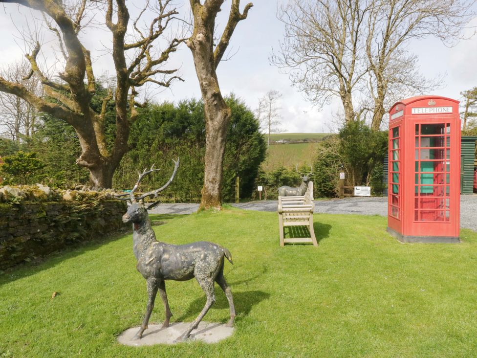 A garden with a deer statue, telephone box, and a bench at Ewedale Farm in Pennington near Ulverston