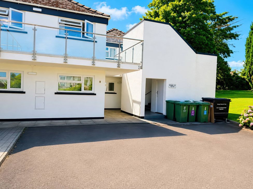 An outdoor view of a building with stairs and bins at 6 Coedrath Park - Swn y Mor, Saundersfoot