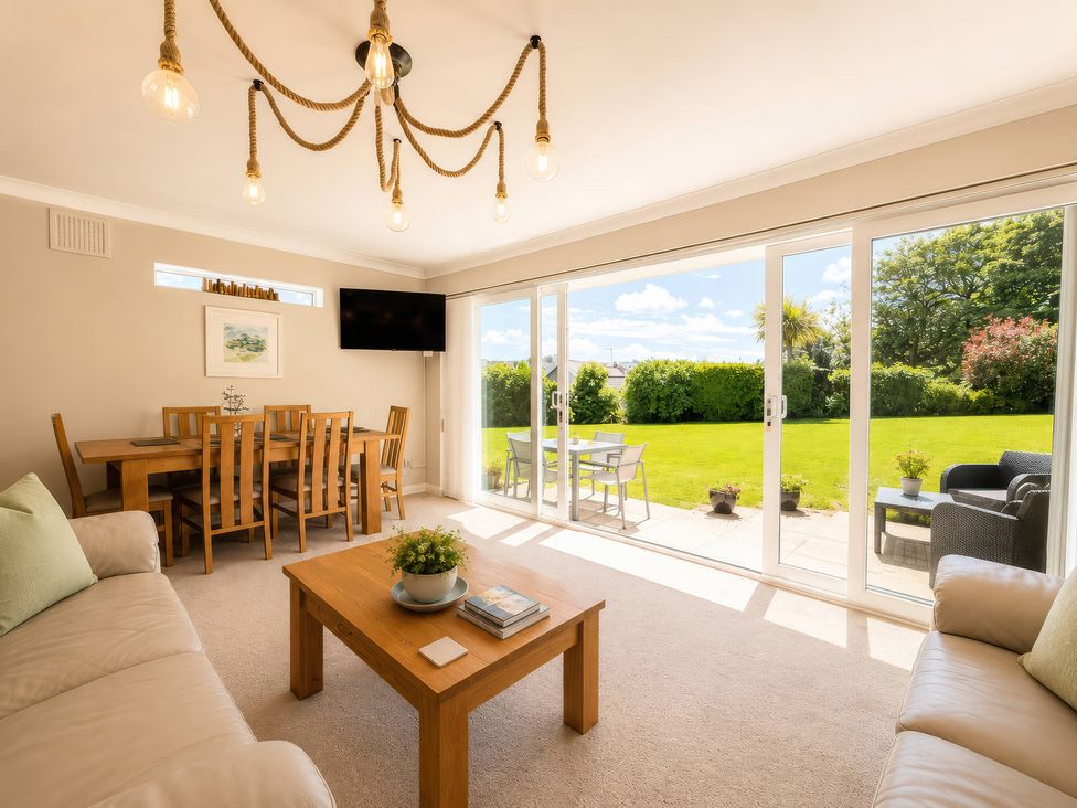 A living room with a dining table and outdoor view at 6 Coedrath Park - Swn y Mor Saundersfoot