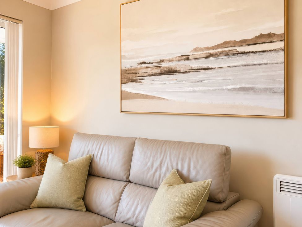 A living room with a sofa and wall art at 6 Coedrath Park - Swn y Mor in Saundersfoot