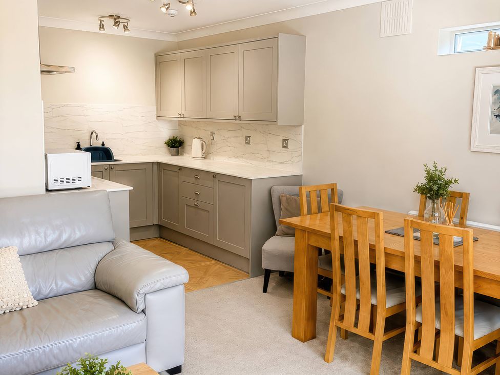 A kitchen and dining area with a table and chairs at 6 Coedrath Park - Swn y Mor in Saundersfoot