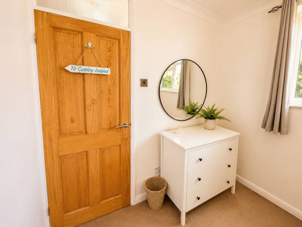 A hallway with a door and dresser at 6 Coedrath Park - Swn y Mor Saundersfoot