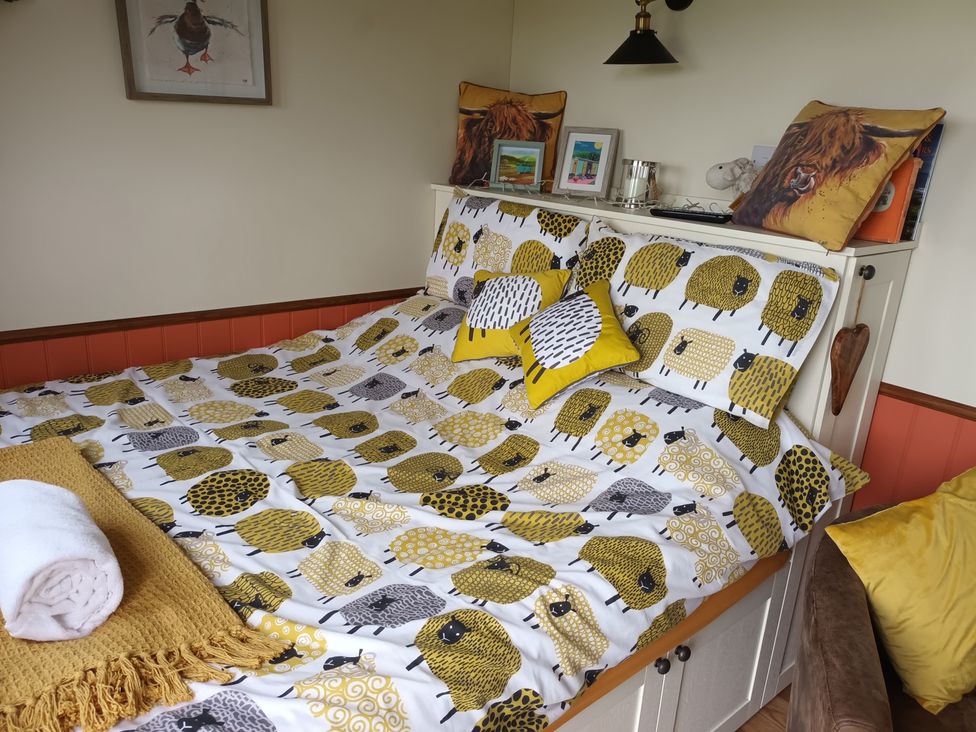 A bedroom with a decorative bed and artwork at The Journeyman Luxury Shepherds Hut in Barnoldswick