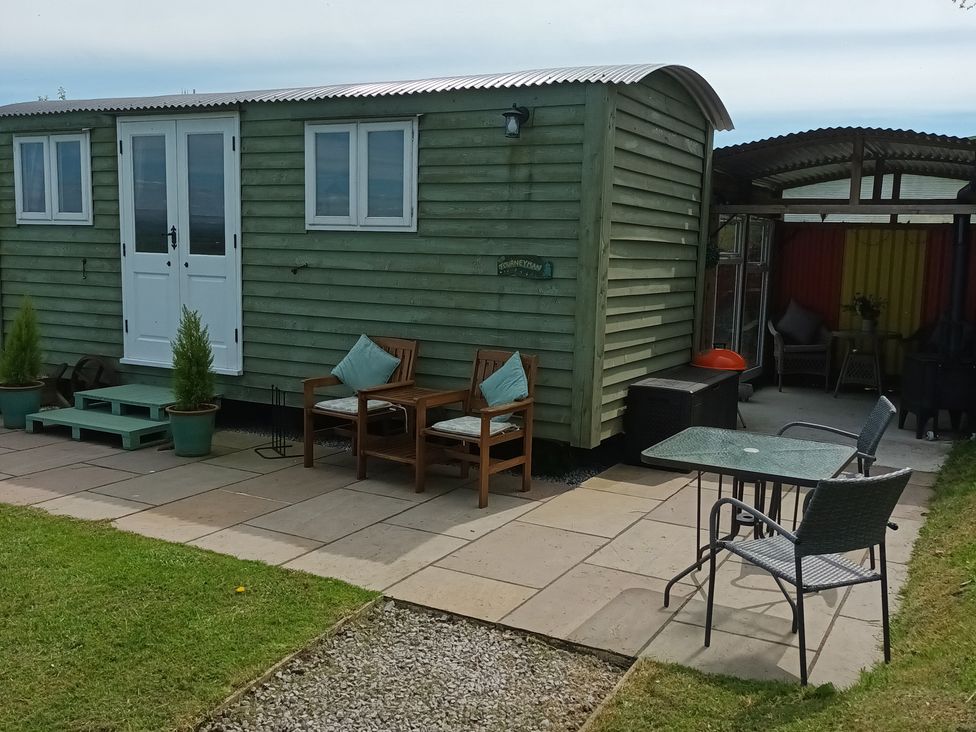 An outdoor area with a shepherd's hut and seating at The Journeyman Luxury Shepherds Hut in Barnoldswick