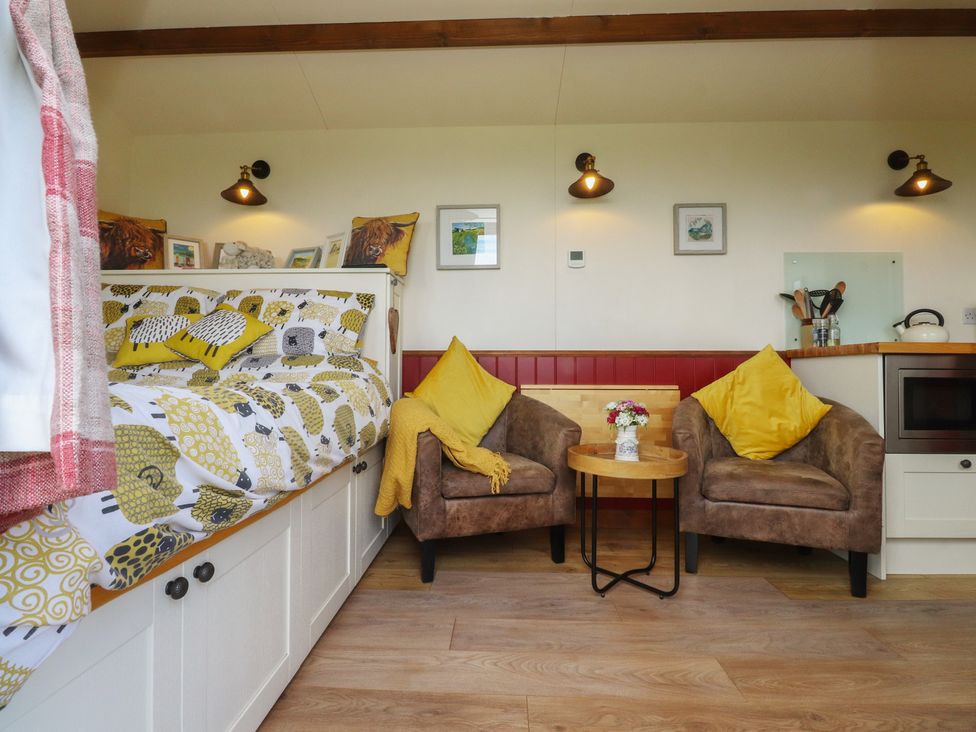 A living room with a bed and armchairs at The Journeyman Luxury Shepherds Hut Barnoldswick