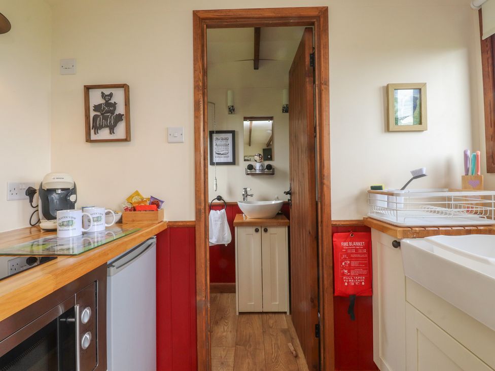 A kitchen with refrigerator and sink leading to a bathroom at The Journeyman Luxury Shepherds Hut in Barnoldswick