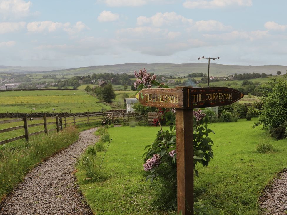 A garden with a signpost and gravel path at The Journeyman Luxury Shepherds Hut in Barnoldswick