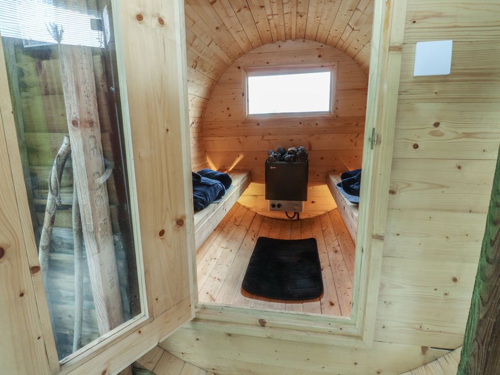 A sauna with wooden benches and heating unit at The Journeyman Luxury Shepherds Hut in Barnoldswick