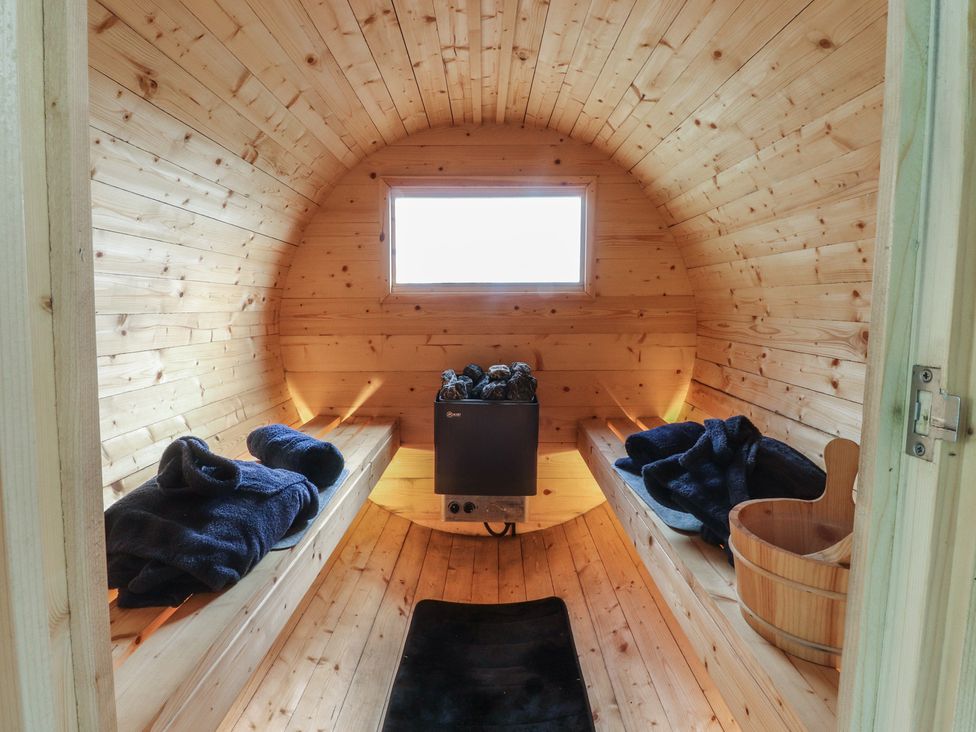 A sauna with wooden benches and a wood stove at The Journeyman Luxury Shepherds Hut in Barnoldswick