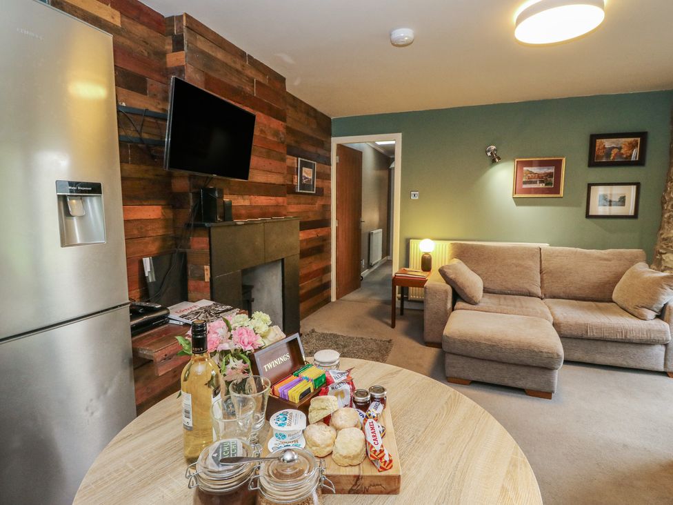 A living room with a sofa, table, and television at Puidrac Cottage Balquhidder