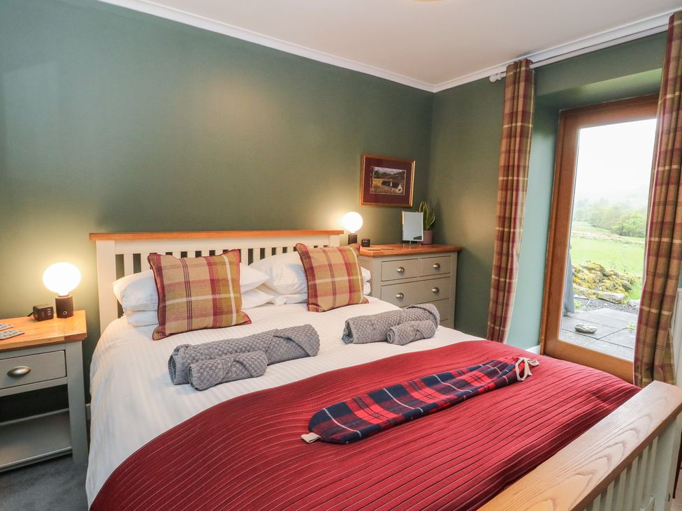 A bedroom with a bed and window at Puidrac Cottage Balquhidder