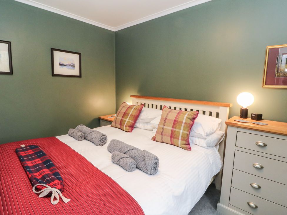 A bedroom with a bed and dresser at Puidrac Cottage in Balquhidder