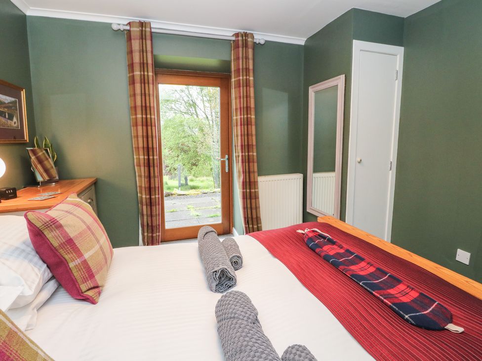 A bedroom with a bed and window at Puidrac Cottage Balquhidder