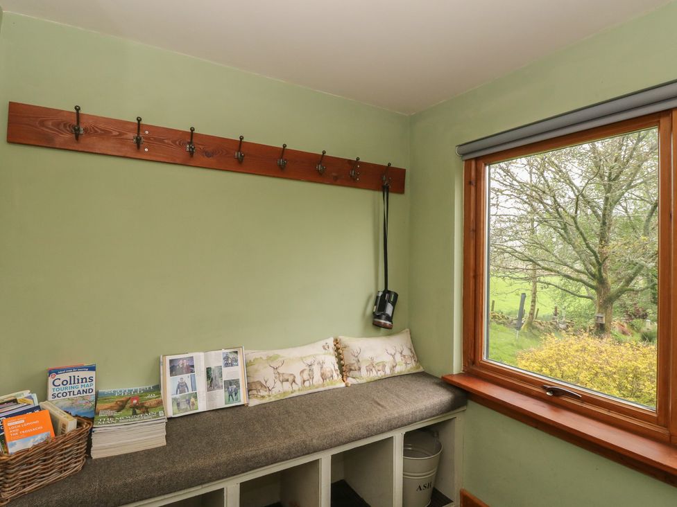 A mudroom with a bench and hooks at Puidrac Cottage in Balquhidder