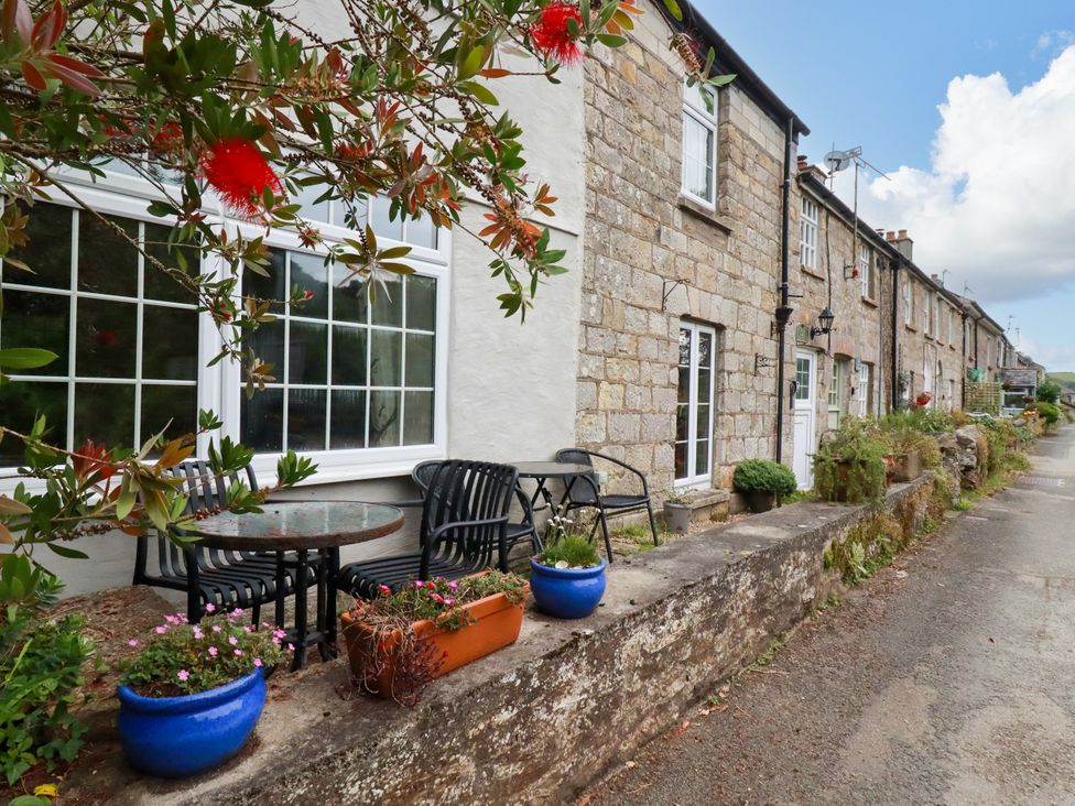 An outdoor seating area with plants and stone wall at Vi’s Valley View in Pentewan
