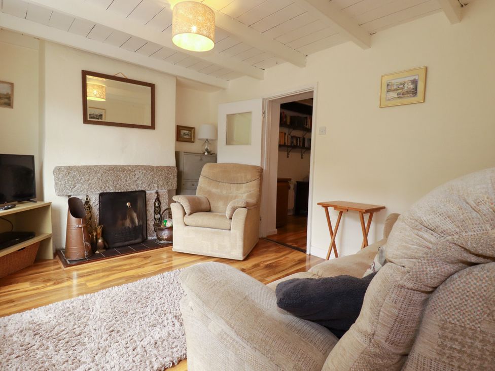 A living room with a fireplace and armchair at Vi’s Valley View in Pentewan