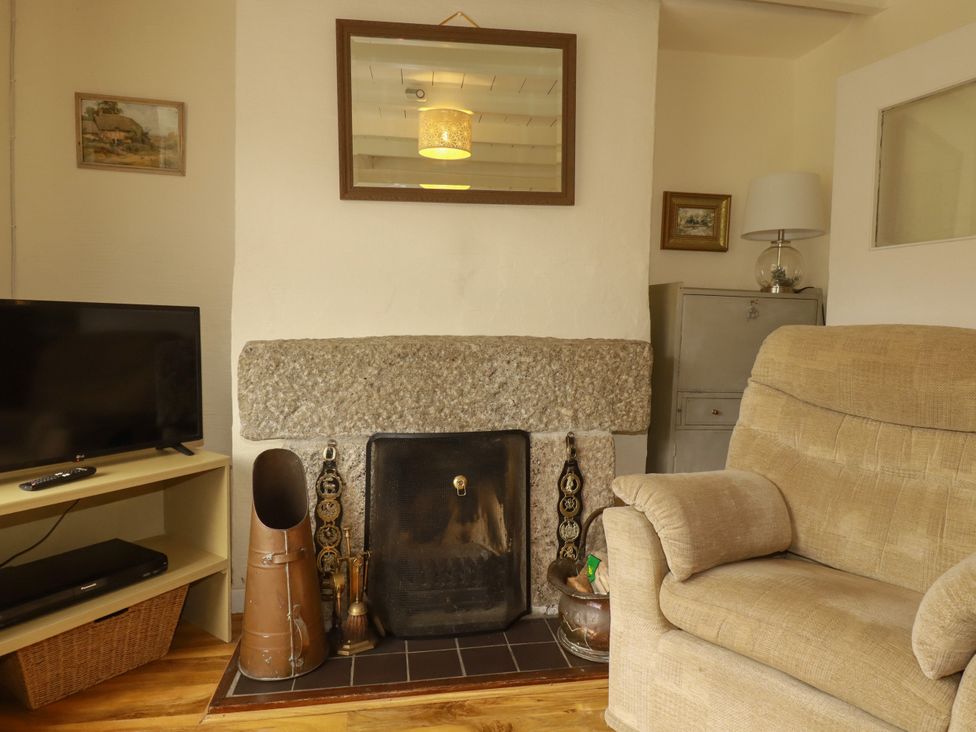 A living room with a fireplace and a television at Vi’s Valley View, Pentewan