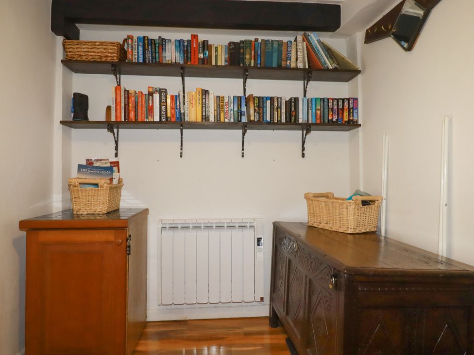 A snug with bookshelves and wooden furniture at Vi’s Valley View in Pentewan