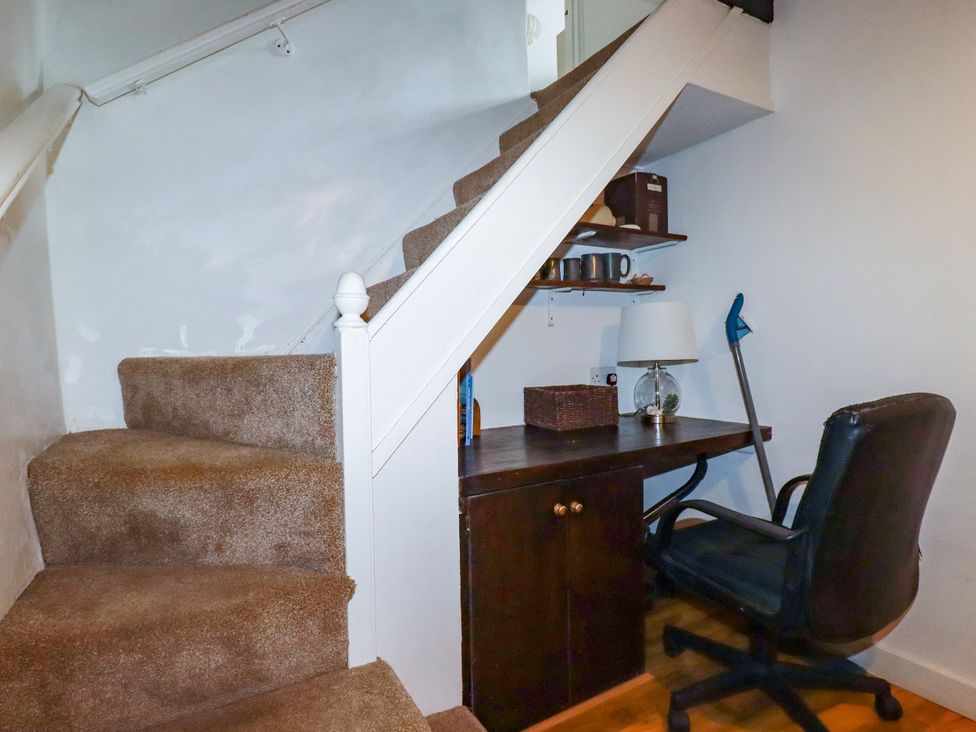 A home office area with desk and chair under the stairs at Vi’s Valley View in Pentewan