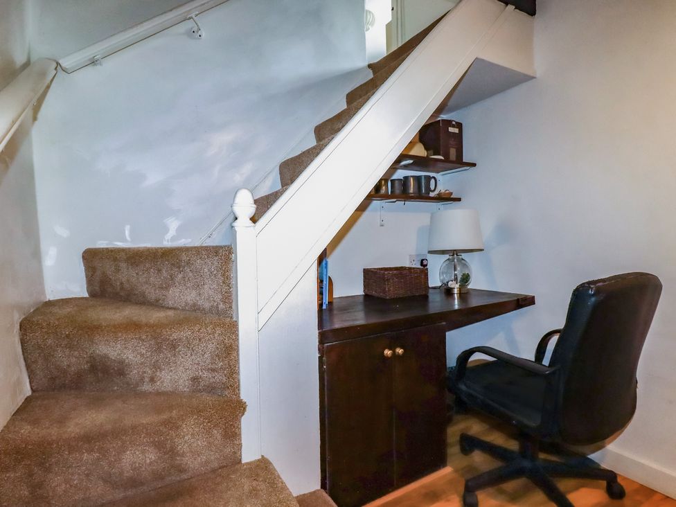 A home office area with a desk and chair under the staircase at Vi’s Valley View Pentewan