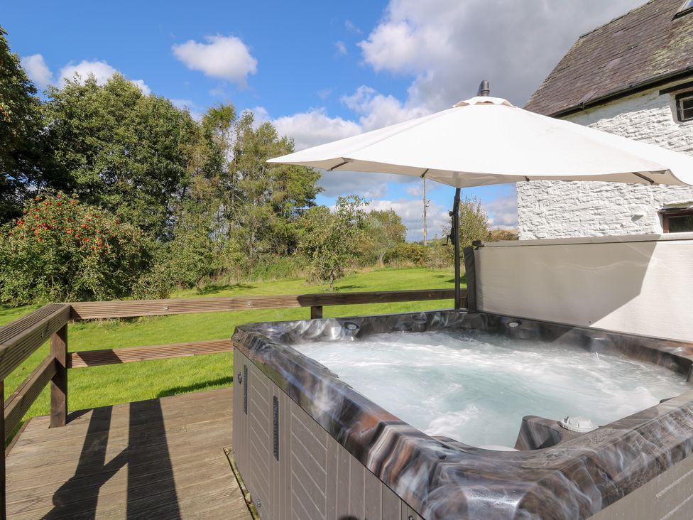 An outdoor area with a hot tub and a parasol at Penarth in Cregrina near Builth Wells