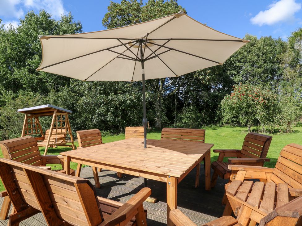 A patio with a wooden table and chairs under an umbrella at Penarth in Cregrina near Builth Wells