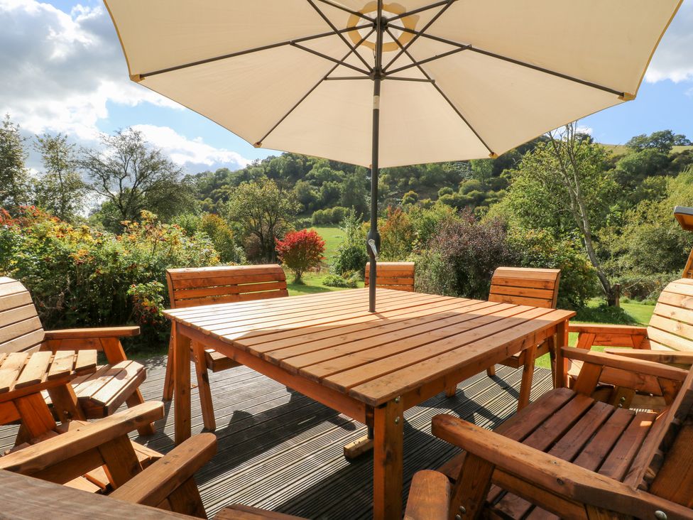 A wooden table and chairs with an umbrella in a garden at Penarth Cregrina near Builth Wells