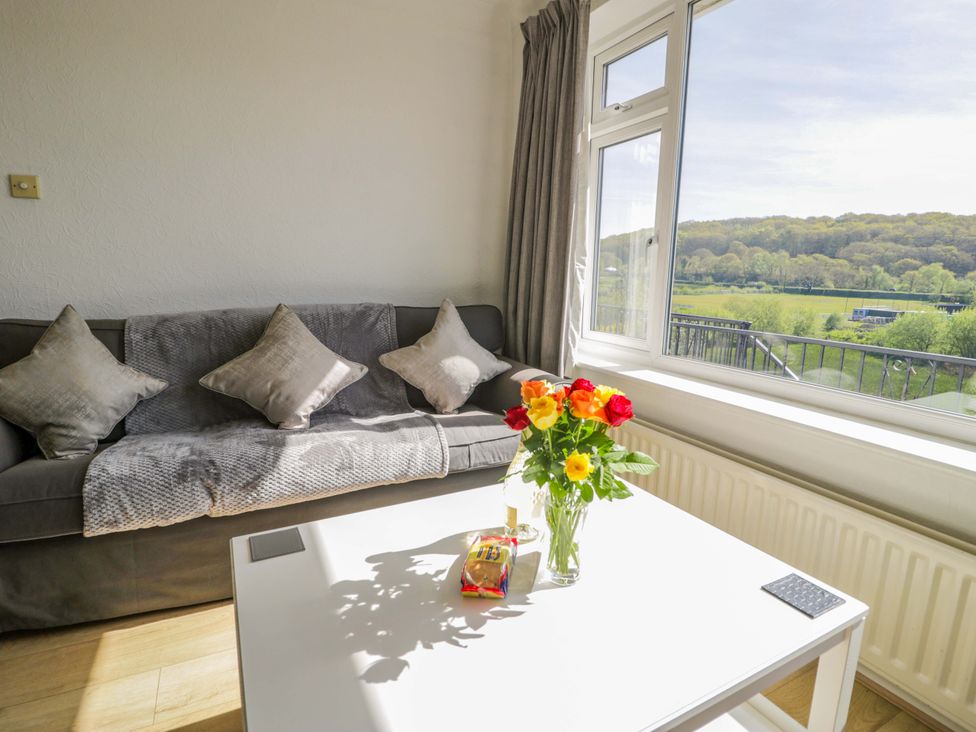 A living room with a sofa and flowers on a table at Trem Y Foel in Penrhyndeudraeth