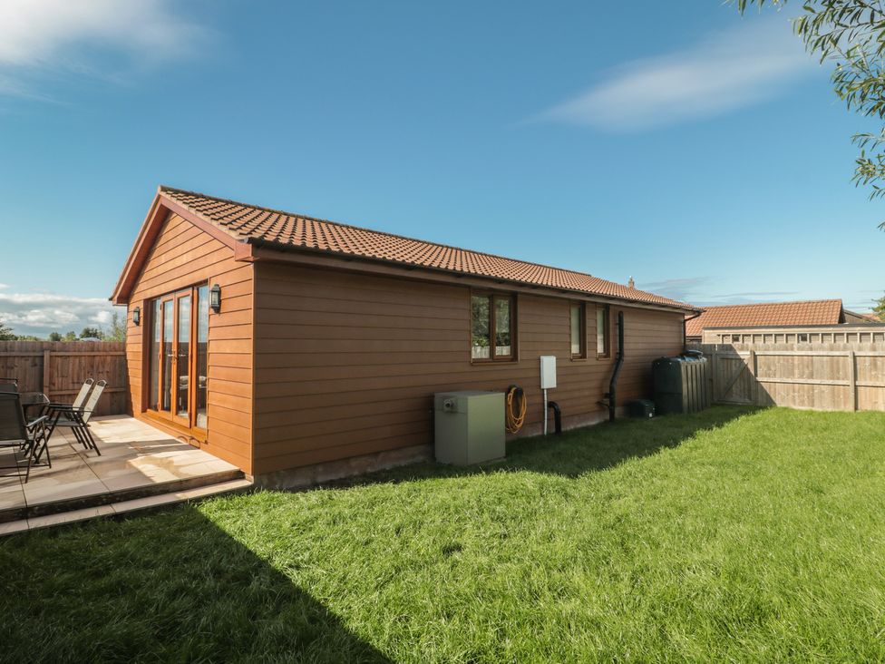 An outdoor view of a house with patio and grass at Bluebell Lodge, Meadow view lodges Brean