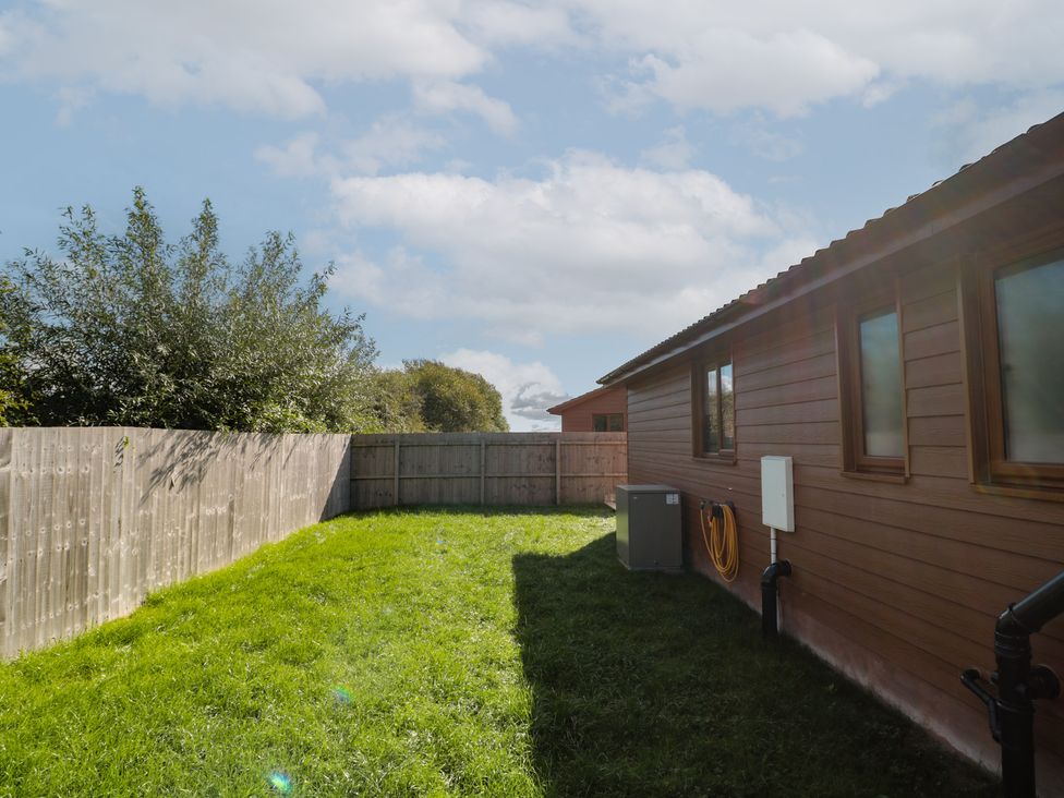 A garden with grass and a fence at Bluebell Lodge, Meadow view lodges Brean