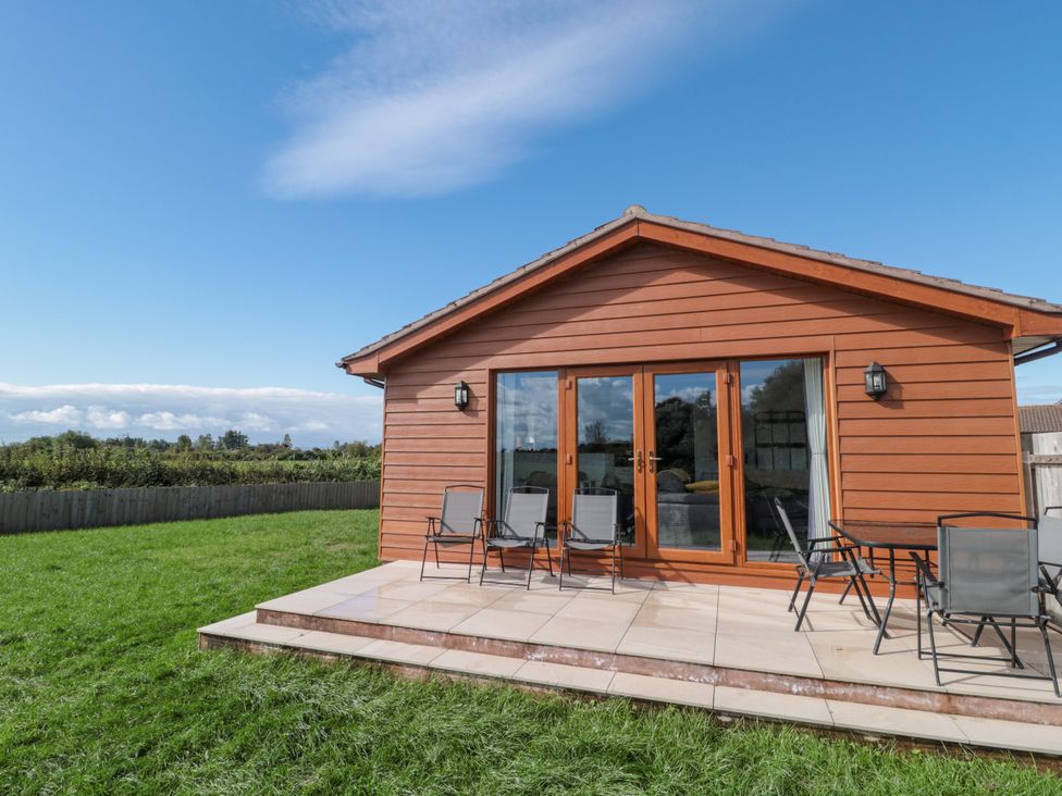 An outdoor area with a cabin and chairs at Delphine Lodge, Meadow View Lodges Brean