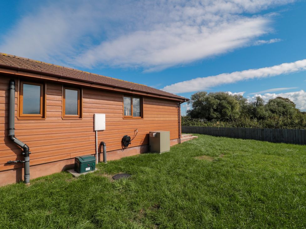 An exterior view of a wooden house with grass at Delphine Lodge, Meadow View Lodges Brean