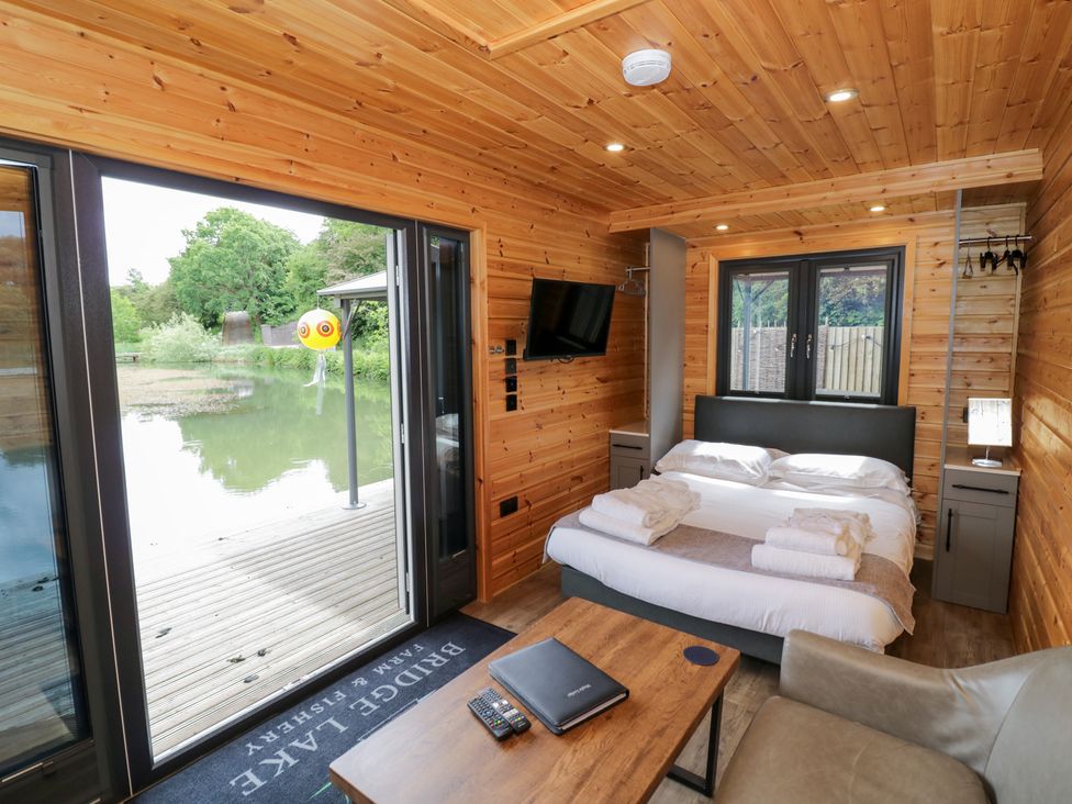 A bedroom with a bed and a television at Maple Lodge at Bridge Lake Farm & Fishery Chacombe