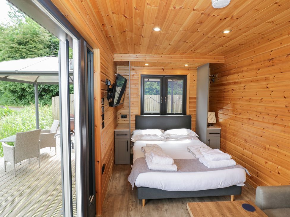 A bedroom with a bed and television at Maple Lodge at Bridge Lake Farm & Fishery Chacombe