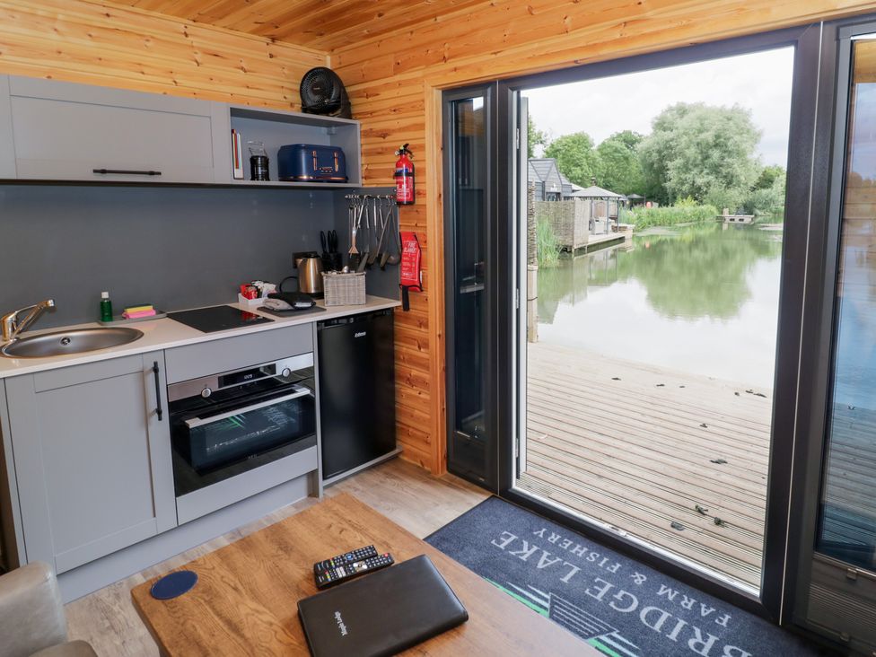 A kitchen with a view of a pond at Maple Lodge at Bridge Lake Farm & Fishery Chacombe