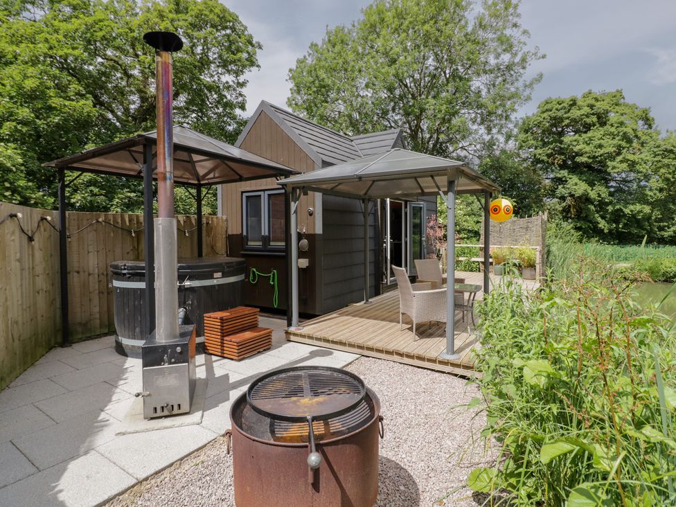 An outdoor space with a hot tub and seating area at Maple Lodge at Bridge Lake Farm & Fishery Chacombe