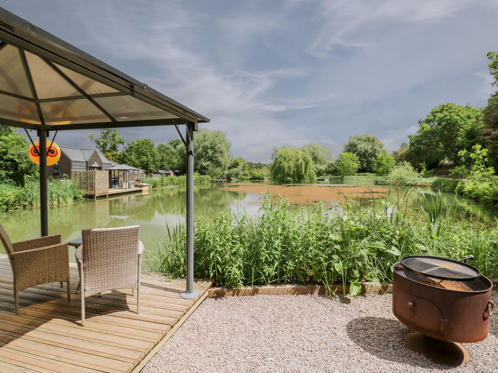 An outdoor area with chairs and a pond at Maple Lodge at Bridge Lake Farm & Fishery Chacombe