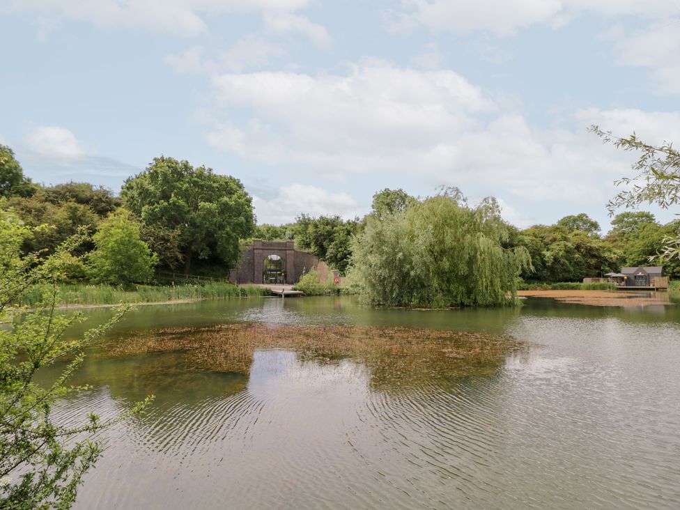 A lake with trees and a bridge at Maple Lodge at Bridge Lake Farm & Fishery Chacombe