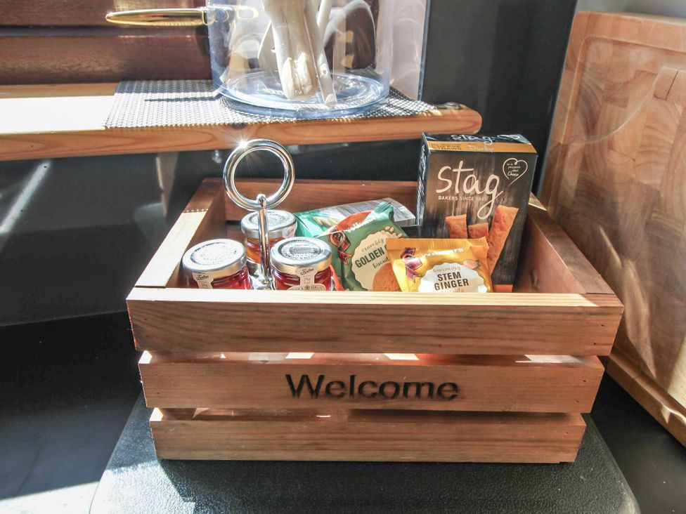 A wooden crate with snacks and jars in the kitchen at Otter Cottage Scarista near Leverburgh