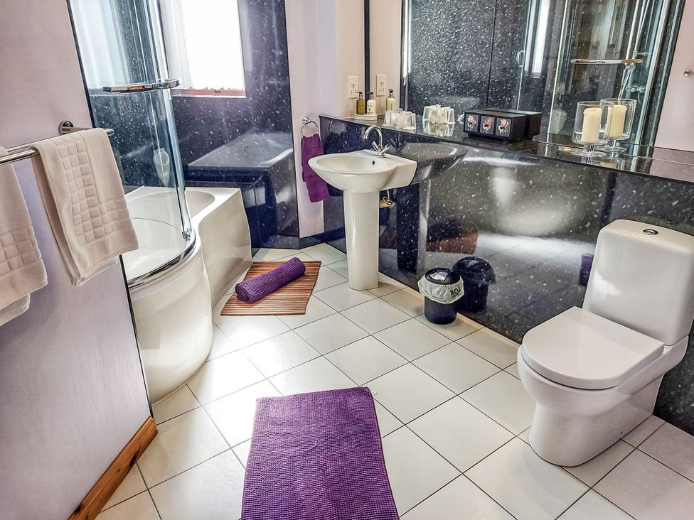A bathroom with a shower and bathtub at Otter Cottage in Scarista near Leverburgh
