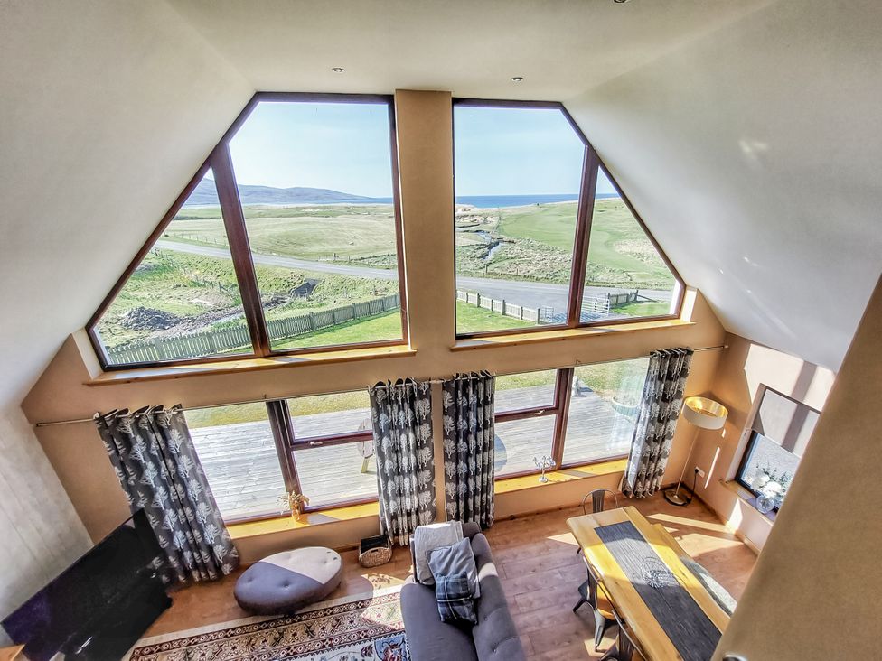 A living room with large windows and a view at Otter Cottage Scarista near Leverburgh