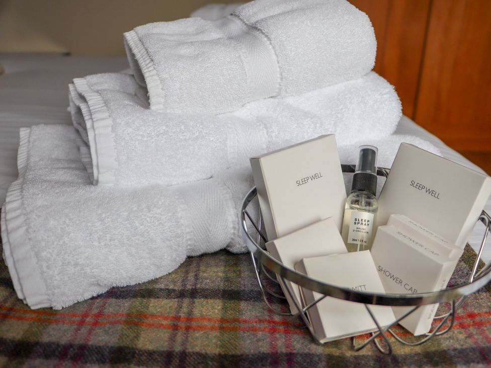 A collection of towels and toiletries in a basket at Otter Cottage Scarista near Leverburgh